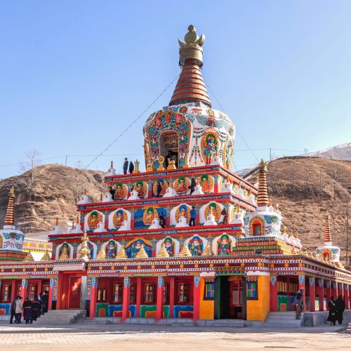 Colorful Tibetan stupa under clear blue sky at Serxu Monastery in China, showcasing traditional architecture.