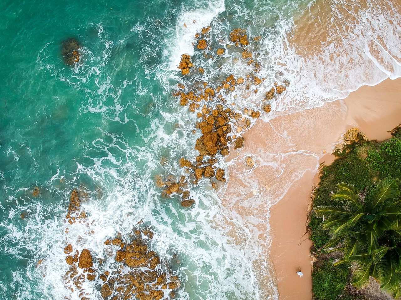 Stunning aerial view of a tropical beach with waves breaking on the sandy shore in Brazil.